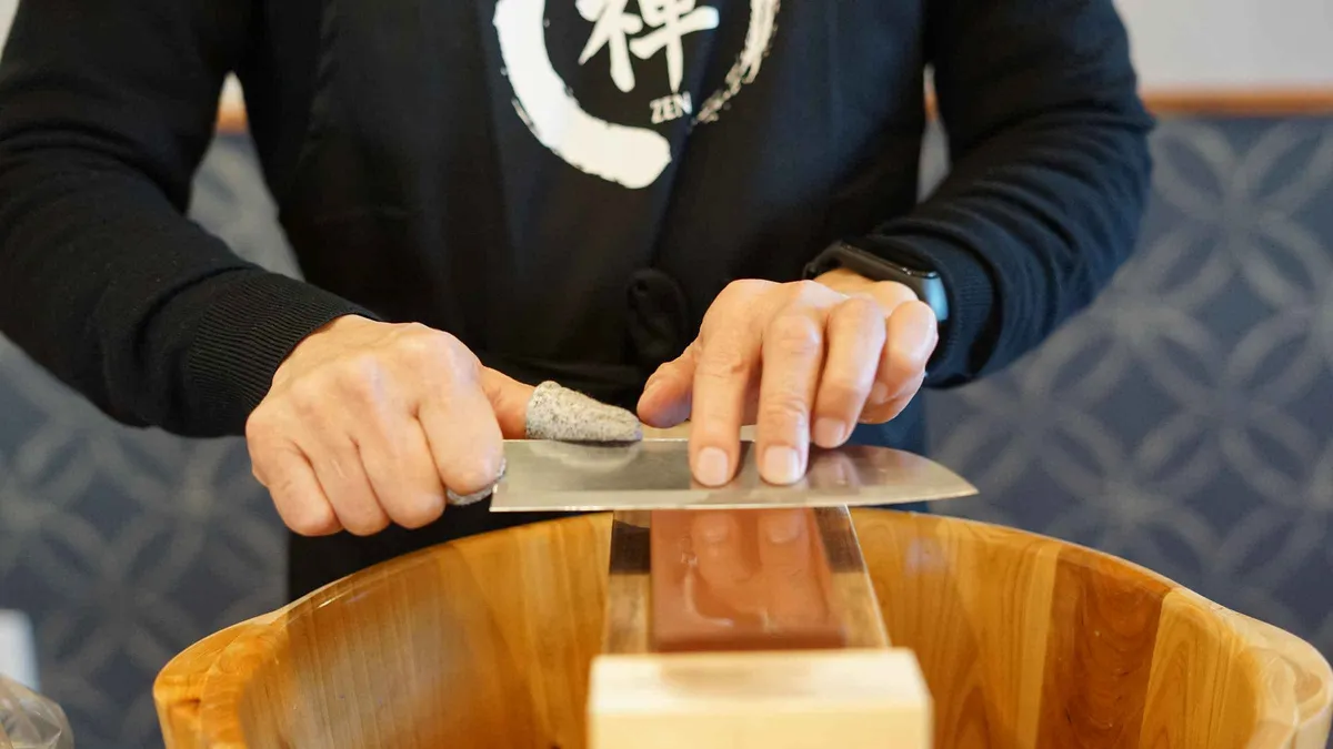 Traveler sharpening a blade on a whetstone during a Japanese knife-making workshop in Asakusa, Tokyo