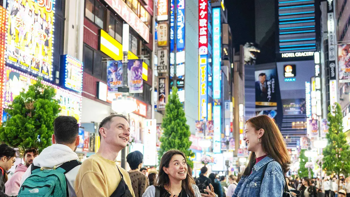 Guide leading visitors past neon signs in Kabukicho on a Shinjuku nightlife walking tour, Shinjuku Tokyo
