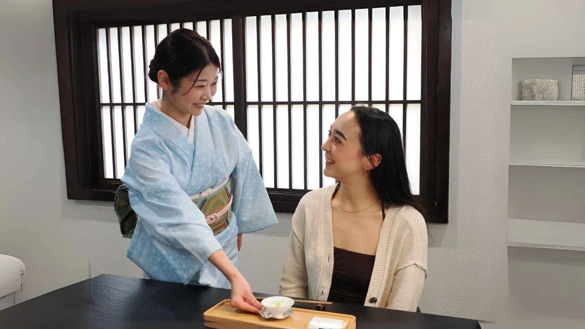 Guest whisking matcha under a tea master's guidance during a Tokyo tea ceremony experience, Tokyo Japan